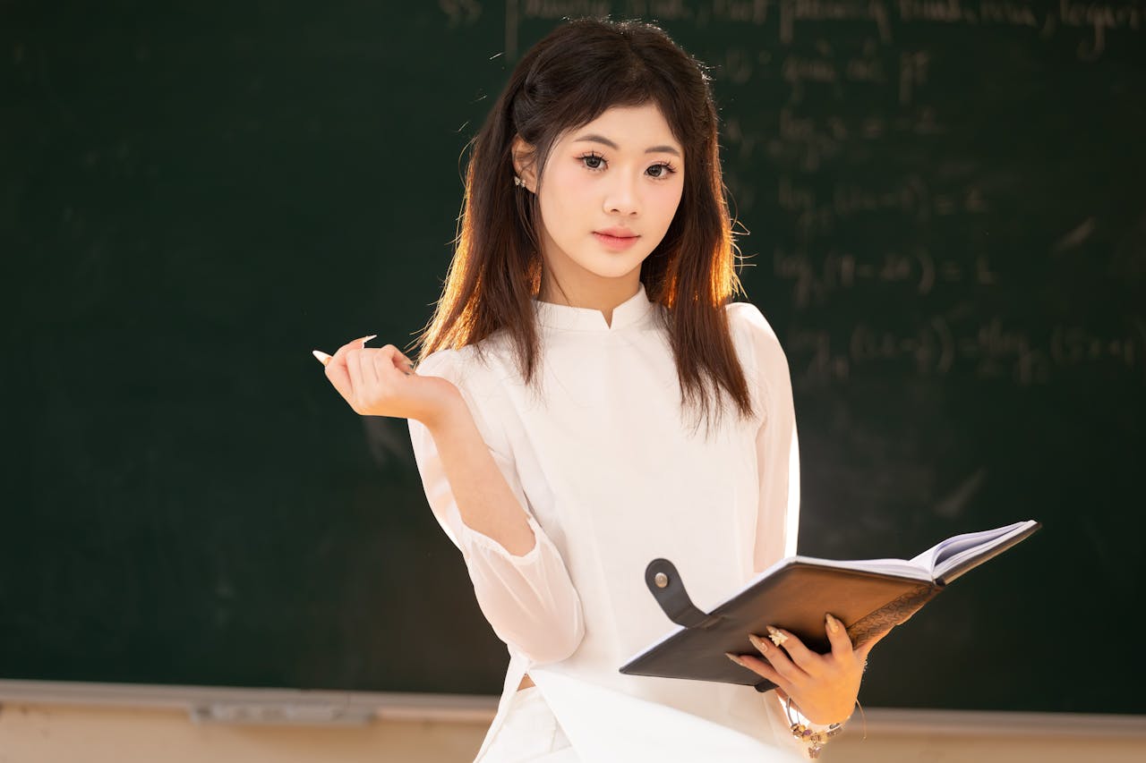Young woman in traditional dress studying in a classroom in Hanoi, Vietnam.