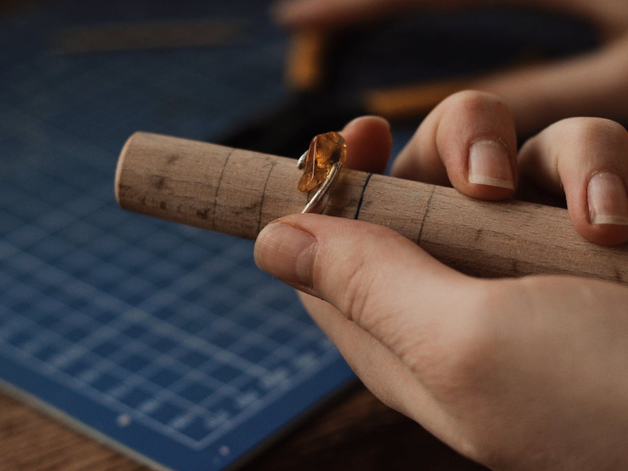 A jeweler crafting a gemstone ring on a mandrel, showcasing intricate handmade craftsmanship.